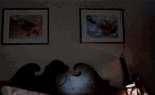 a woman is holding her head in pain while talking on a cell phone in a dark room .