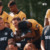 a group of soccer players are hugging and laughing with jd on their shirts