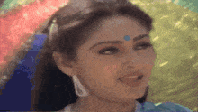a woman with a blue dot on her forehead is smiling