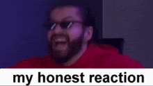 a bearded man wearing sunglasses is laughing with his mouth open .