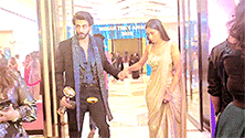 a man and woman are holding hands while walking through a glass door .