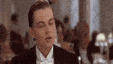leonardo dicaprio is wearing a tuxedo and bow tie while sitting at a table .