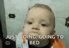 a baby is making a funny face and says `` just doing , going to bed '' .