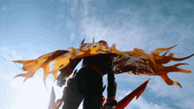 a person holding a sword and a cape that looks like fire
