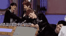 a group of young men are sitting around a table laughing and playing a game .