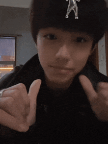 a person wearing a black jacket and a silver ring making a heart shape with their fingers