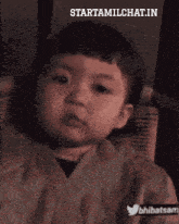 a baby is sitting in a chair with the words starttamilchat.in on the bottom