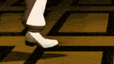 a person wearing white shoes is walking on a tiled floor .