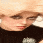 a close up of a woman 's face wearing a black shirt and making a funny face .