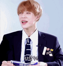 a young man in a suit and tie is holding a blue bottle that says nub drop on it
