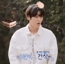 a man in a white jacket has a hand on his head and a piece of cake behind him