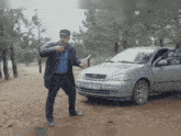 a man is standing in front of a car with a license plate that says tc 257-ku