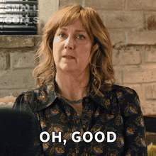 a woman says " oh good " in front of a brick wall