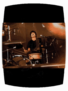a man in a black shirt is playing drums