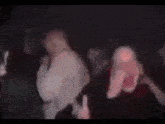 a blurry picture of a man making a stop sign in a dark room .