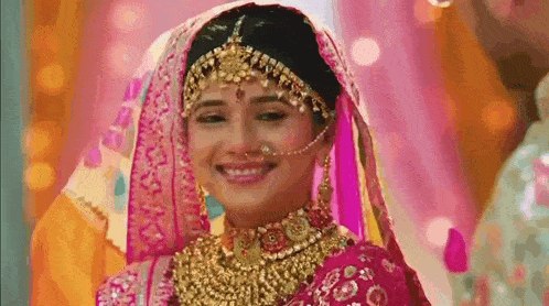 a bride in a pink and gold wedding dress is smiling .