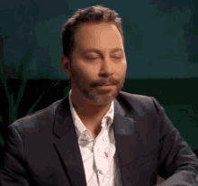 a man with a beard is wearing a suit and a white shirt .