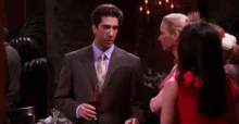a man in a suit and tie is talking to two women in a dark room .
