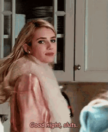 a woman in a fur coat is standing in a kitchen and saying good night sluts .