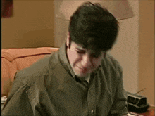 a man in a green shirt is sitting at a desk