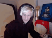 a man wearing a hoodie and headphones is sitting in front of a computer .