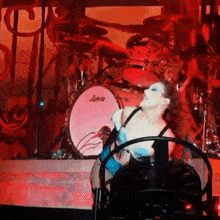 a woman is dancing in front of a ludwig drum set