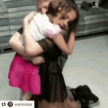 a woman in a black dress is hugging a little girl in a pink skirt ..