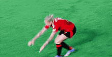 a female soccer player is doing a handstand on a field .