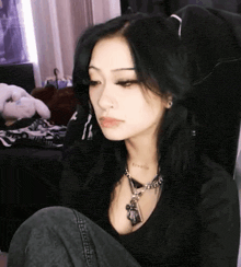 a woman with long black hair is wearing a necklace and a nose ring .