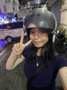 a woman wearing a motorcycle helmet giving a peace sign