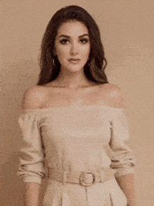 a woman in a off the shoulder sweater is holding her sweater up .