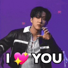 a young man in a leather jacket is holding a pink heart and says `` i love you '' .