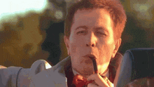 a man in a suit and bow tie is smoking a pipe .