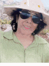 a woman wearing sunglasses and a hat is smiling