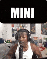 a man wearing headphones and a tank top is sitting in front of a microphone .