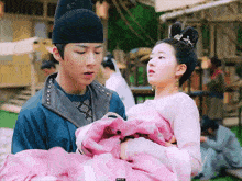 a man is holding a woman in a pink dress