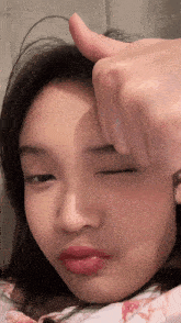 a woman giving a thumbs up sign with her eyes closed