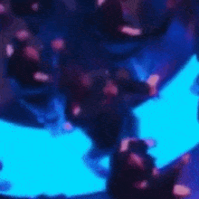 a blurry picture of people dancing in a dark room with blue lights .