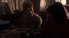 a man and a woman are sitting on a couch talking to each other .