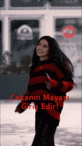 a woman wearing a red and black striped sweater with the words " cekanin mayasi giriş edir " written on the bottom