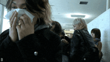 a woman blowing her nose in front of a sign that says ' a ' on it