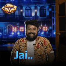 a man with a beard is smiling in front of a sign that says ' jai '