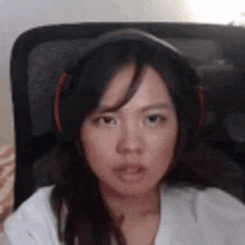 a woman wearing headphones and a white shirt is sitting in a chair .