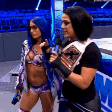 two female wrestlers standing next to each other with one holding a trophy
