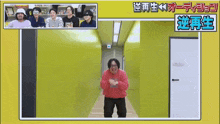 a man in a red sweatshirt is standing in a hallway with a group of people behind him .
