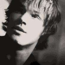 a black and white photo of a man 's face with a shadow on the wall