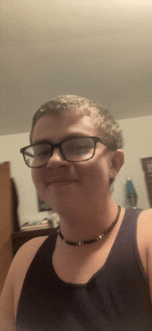 a young man wearing glasses and a choker is smiling for the camera