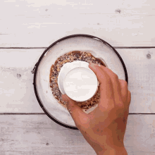 a person pouring a white liquid into a bowl of food
