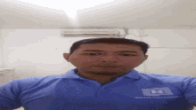 a man wearing a blue shirt with the letter b on it takes a selfie