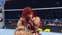 a woman with red hair is wrestling another woman in a wrestling ring